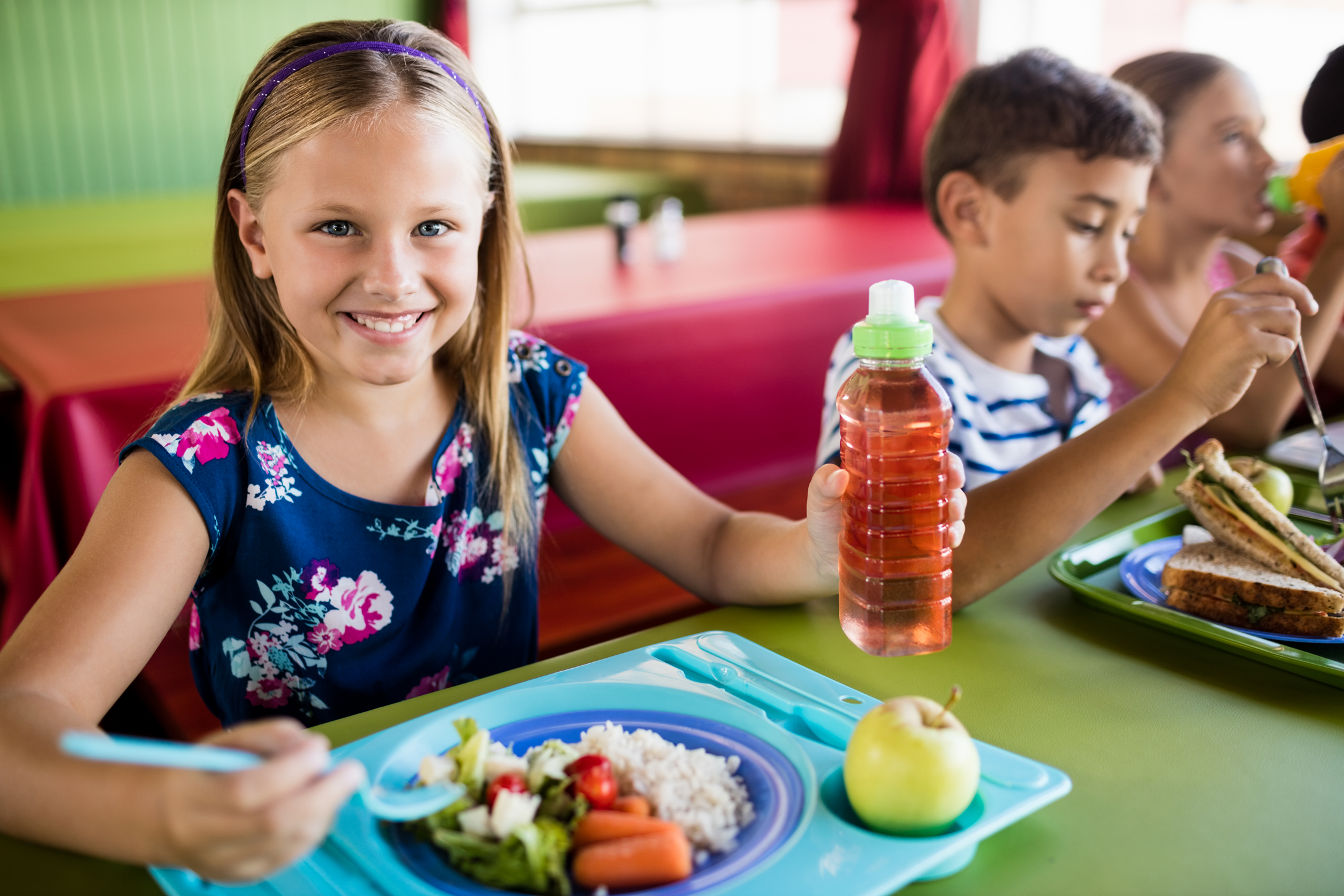 Young girl sitting at lunch eating and drinking