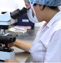 Lab technician looking into microscope
