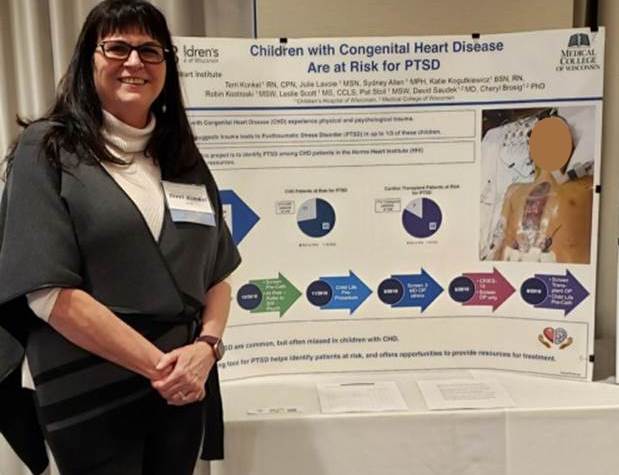 Nurse standing by her research regarding post-traumatic stress disorder in children with congenital heart disease. 