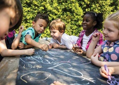 Children outside drawing with chalk together